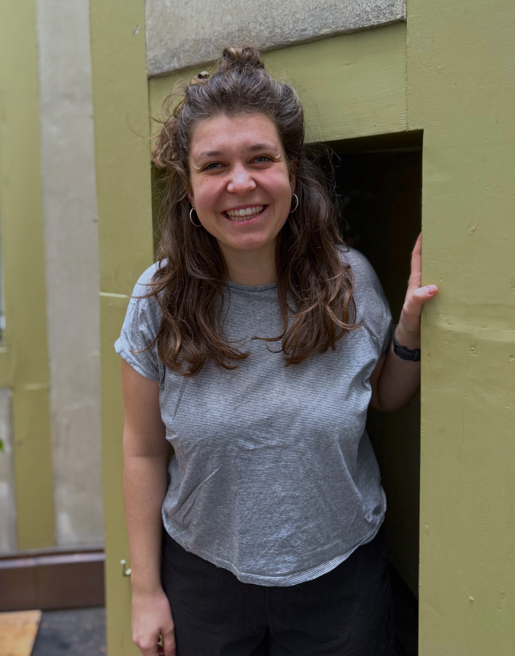 Portrait von Lina, stehend und in Kamera lachend.